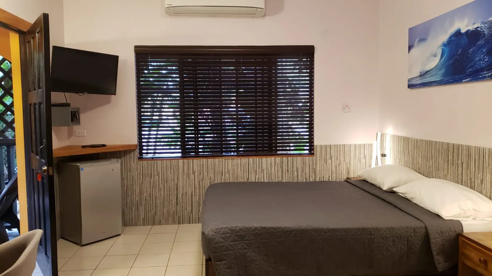 Habitación de Ocean Mist con cama, televisor, mininevera y una obra de arte con olas.