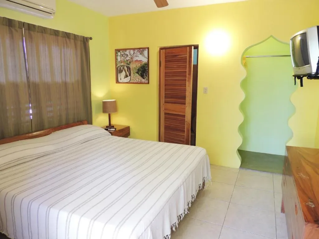 Habitación deluxe king con paredes amarillas, una cama y armario de madera.