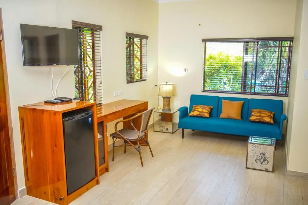 Sala de estar amueblada de la suite con sofá, escritorio, televisor y minirrefrigerador.