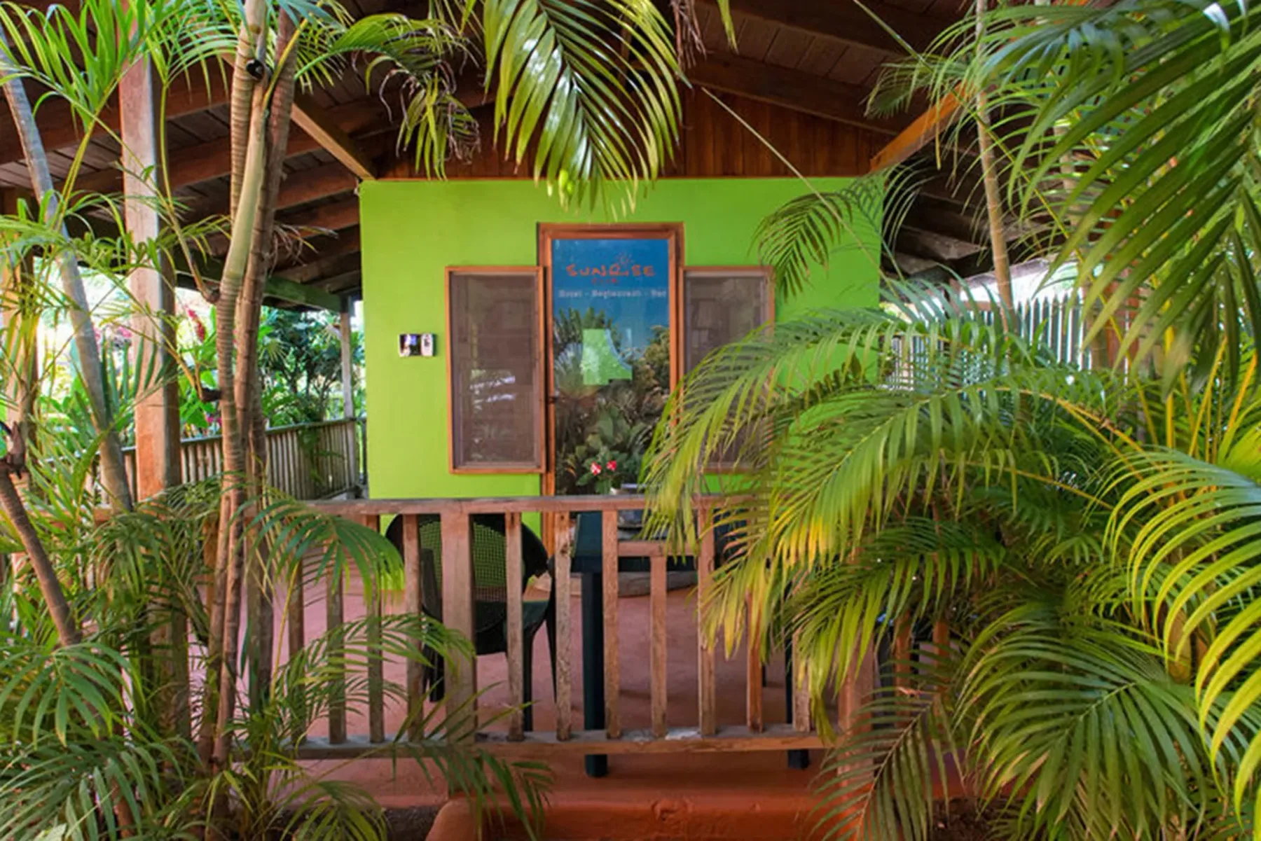 Letrero de entrada del hotel rodeado de plantas tropicales.