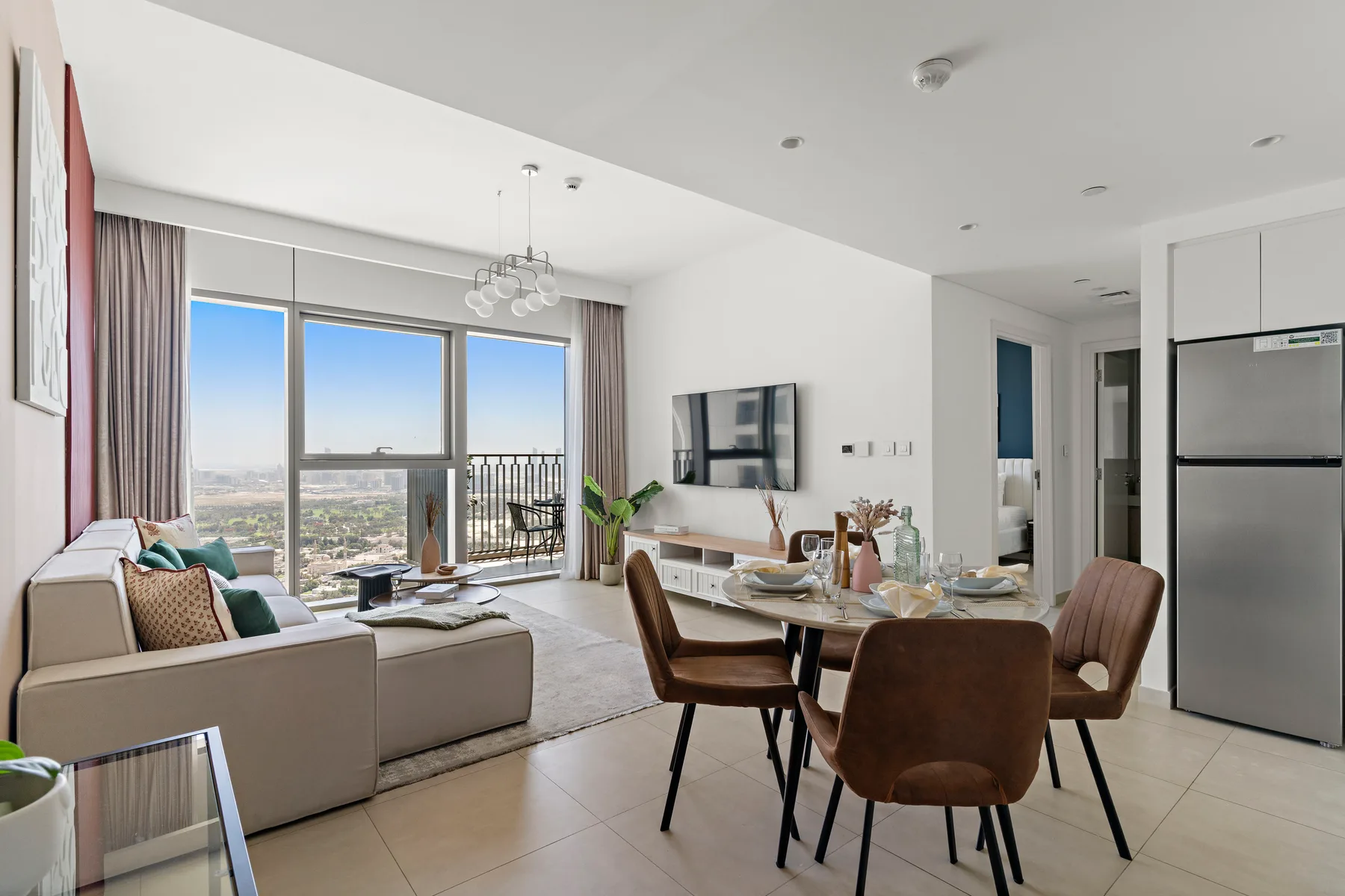 A bright open-plan living and dining area with large windows overlooking the city.