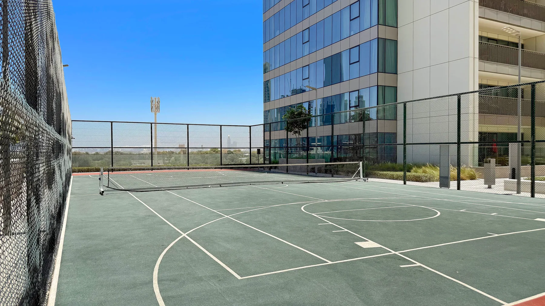 An outdoor sports court with painted lines sits beside a modern building.