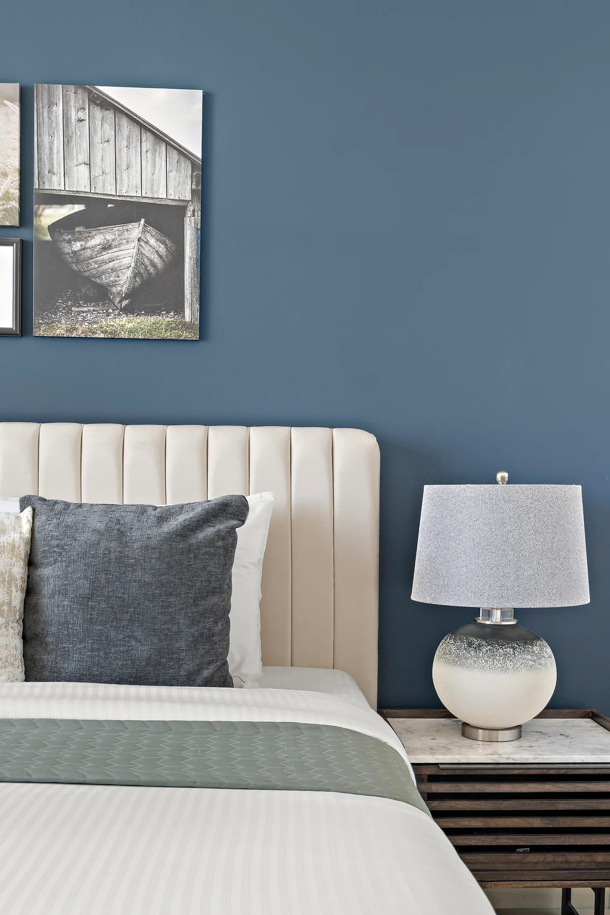 A bedroom with a bed, bedside table, and framed wall art.