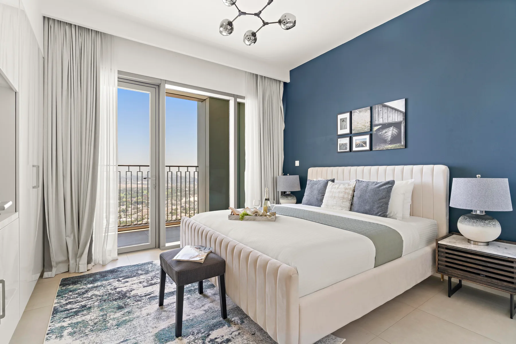 A bright bedroom with a large bed beside glass doors opening onto a balcony.