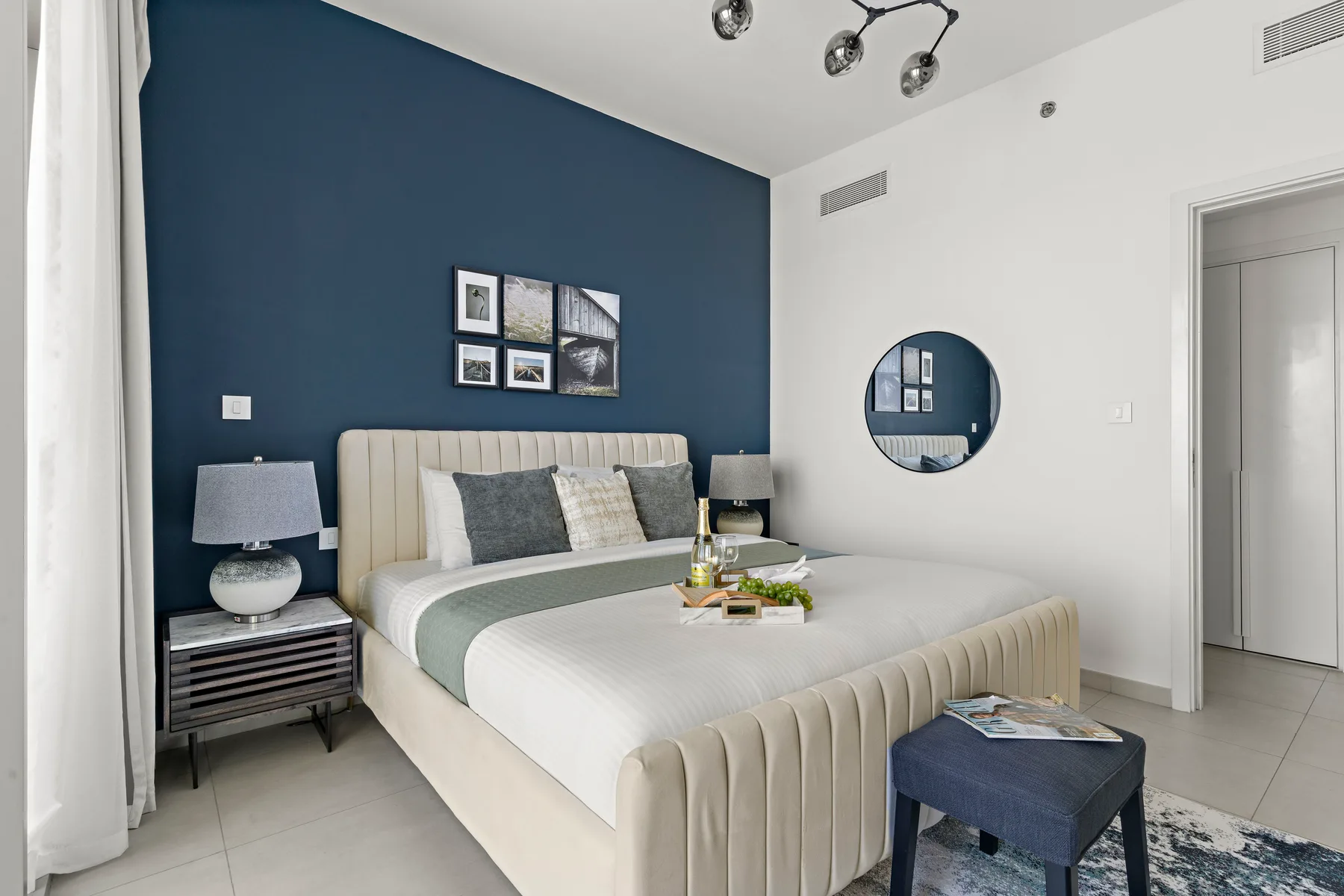 A bedroom with a neatly made bed and a dark blue accent wall.