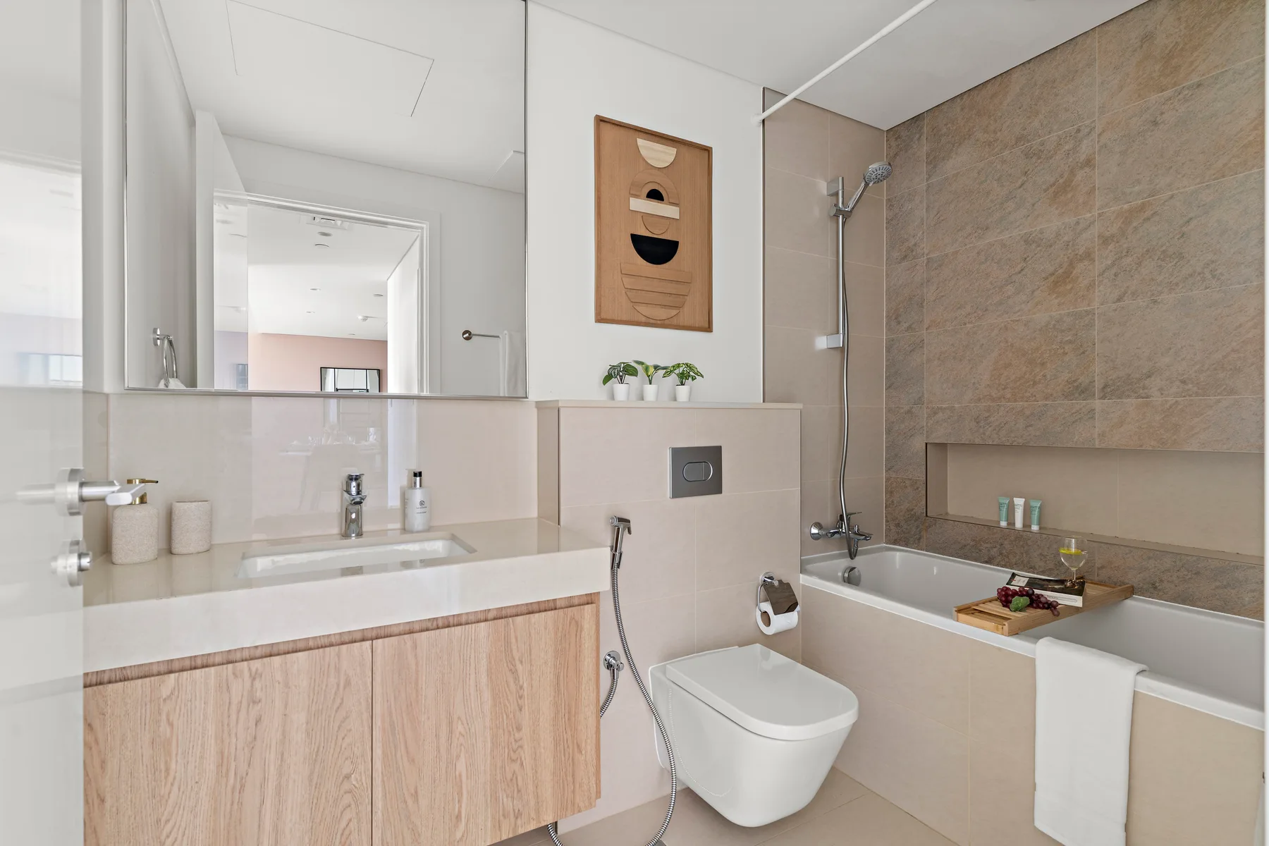 A bright bathroom with a vanity, toilet, and bathtub with a shower.