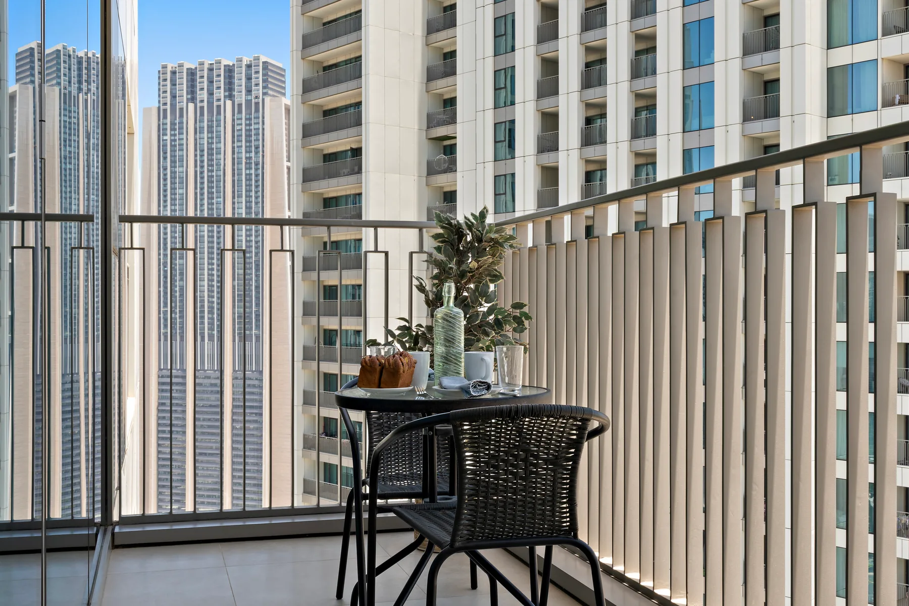 A balcony seating area with a small table and views of nearby high-rise buildings.