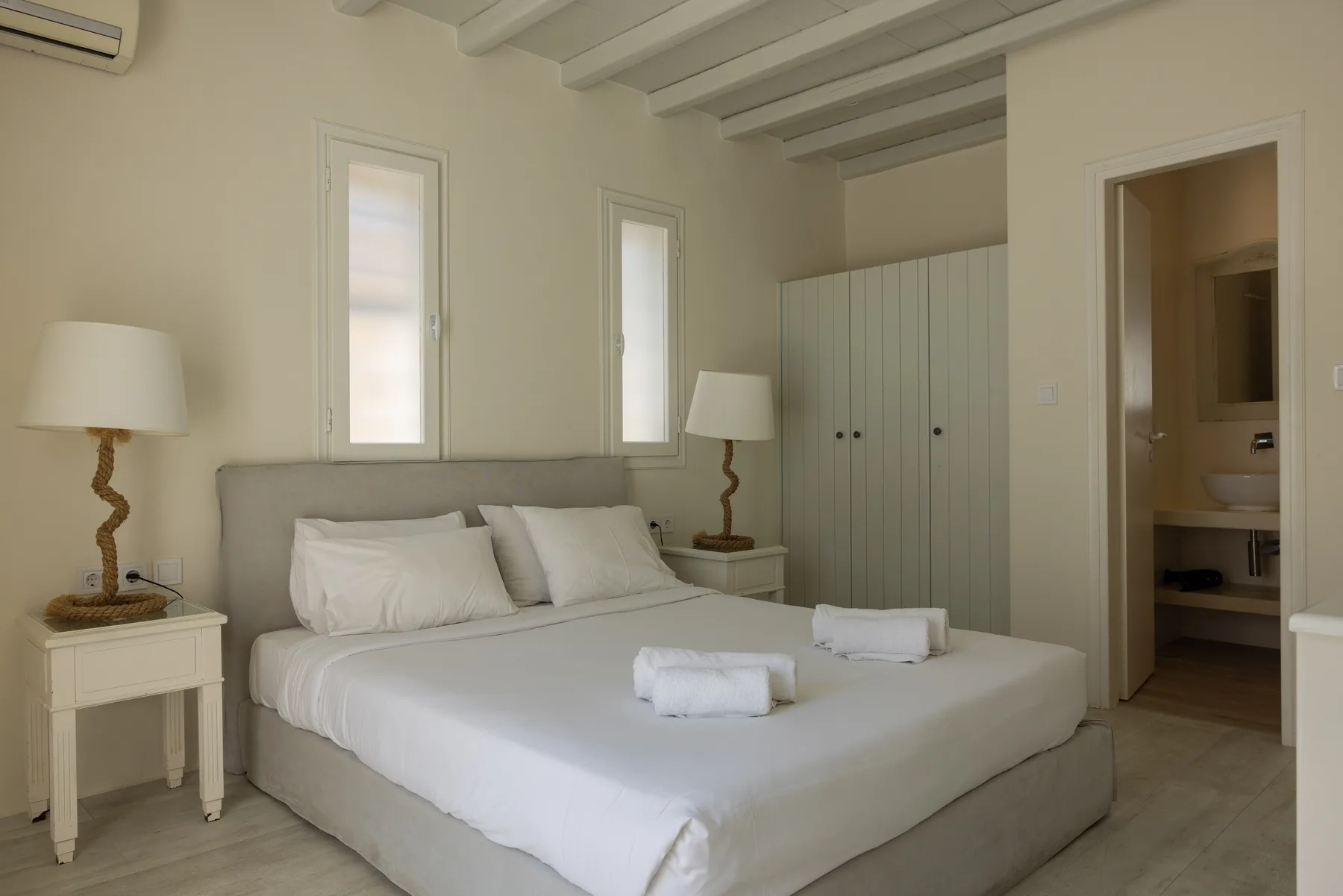 A bedroom with a neatly made bed and white linens.