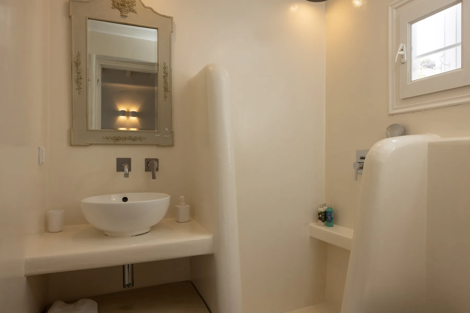 A bathroom with a basin, wall mirror, and shower.