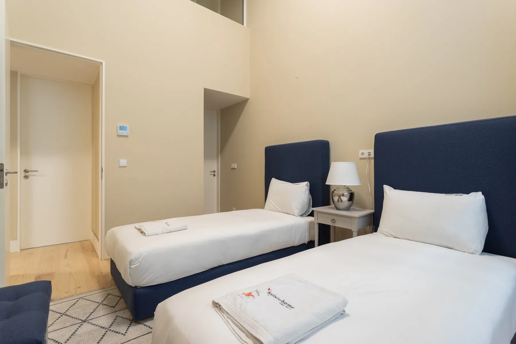 A bedroom with two beds and a bedside table between them.