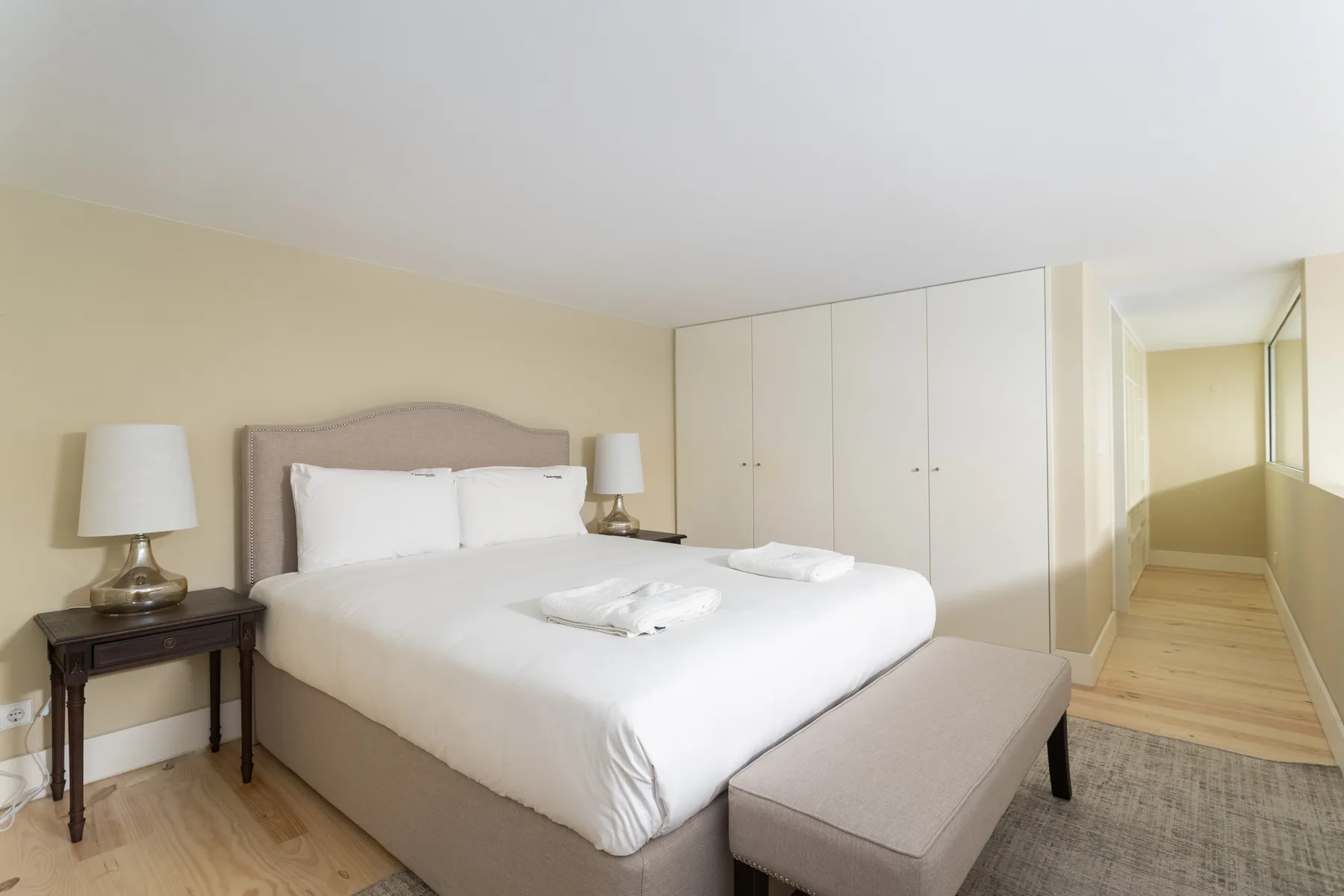 A bedroom with a neatly made bed and white wardrobes.