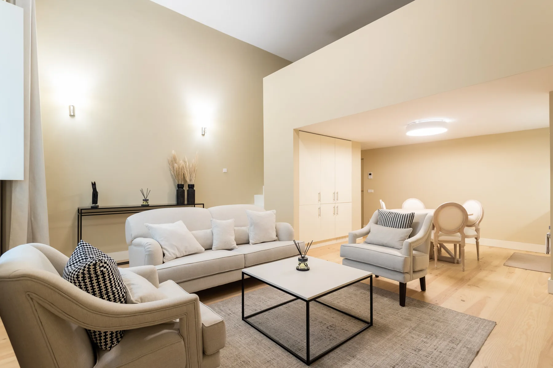 A bright living room with upholstered seating, a coffee table, and a dining area.