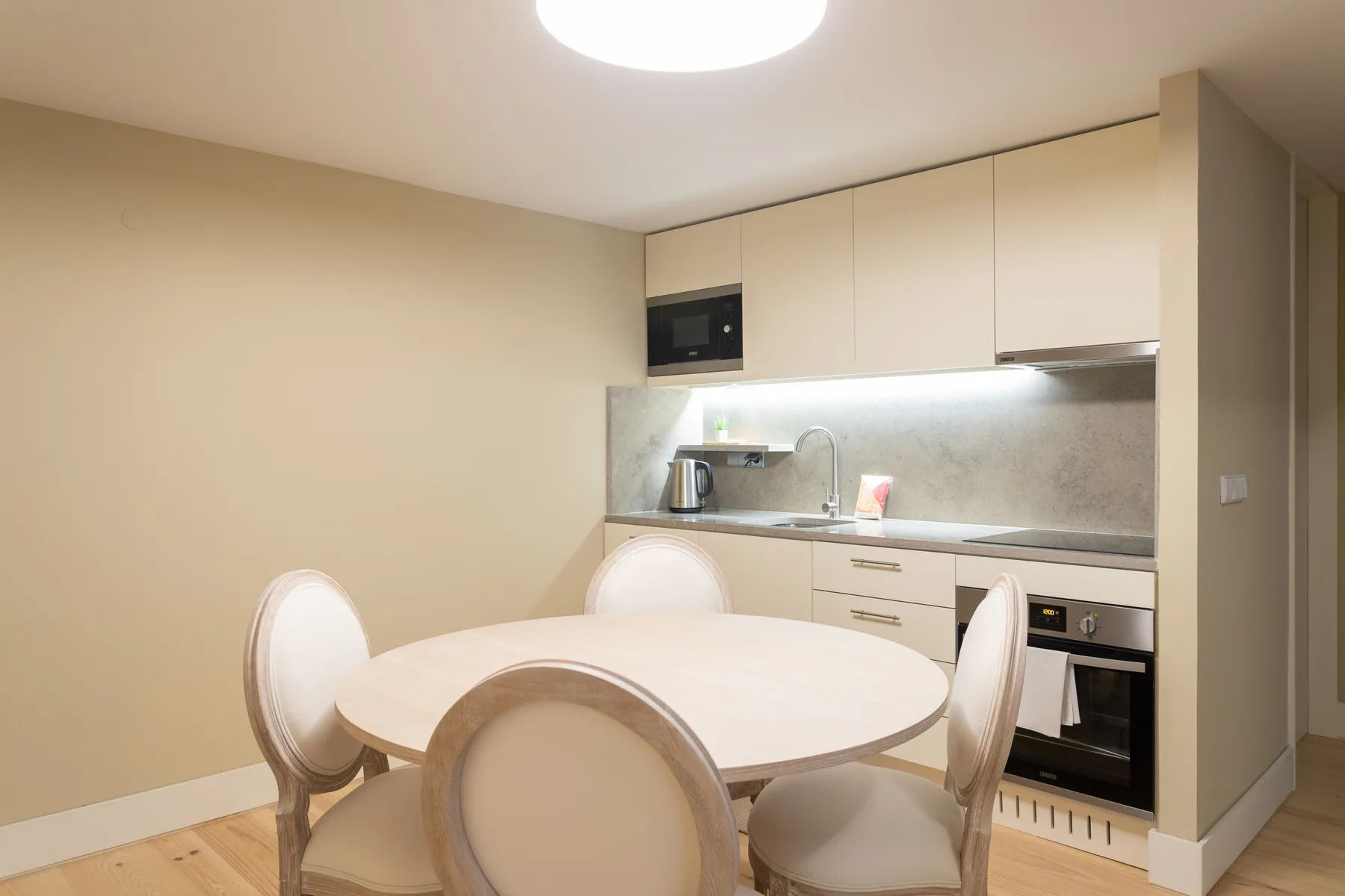A compact kitchen with a round dining table and built-in appliances.