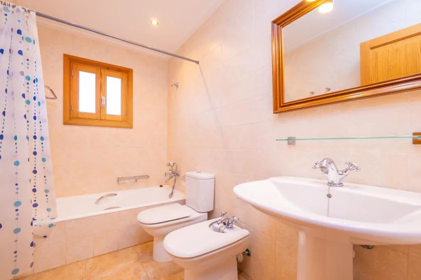 A tiled bathroom with a bathtub, toilet, bidet, and sink.