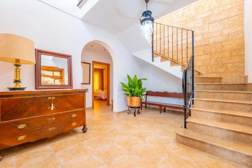 A bright interior foyer with a staircase, wooden console, and potted plant.