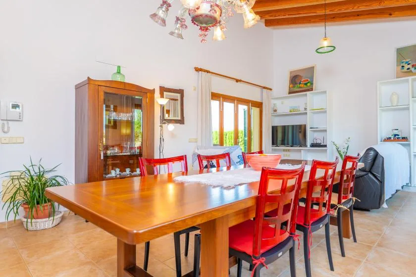 A dining room with a long wooden table and red seating.