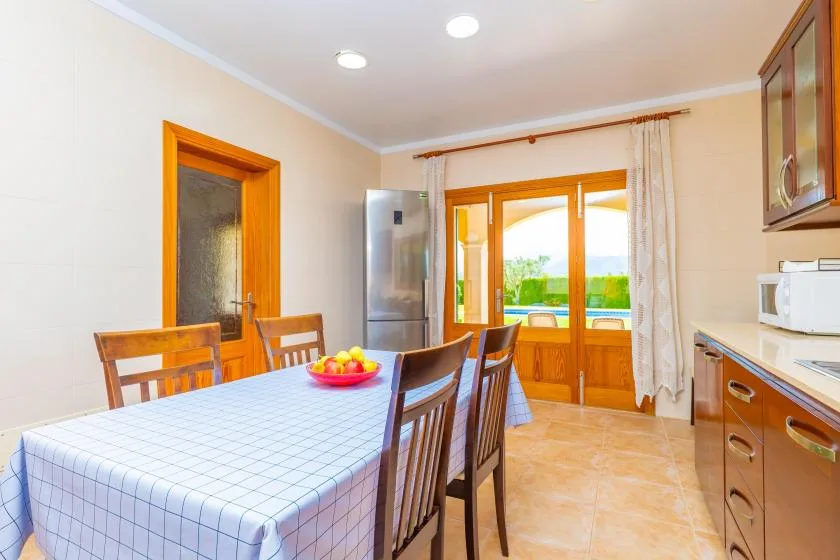 A bright kitchen and dining area with a table beside wooden-framed windows.