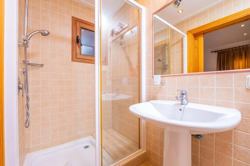 A tiled bathroom with a glass shower and a pedestal sink.
