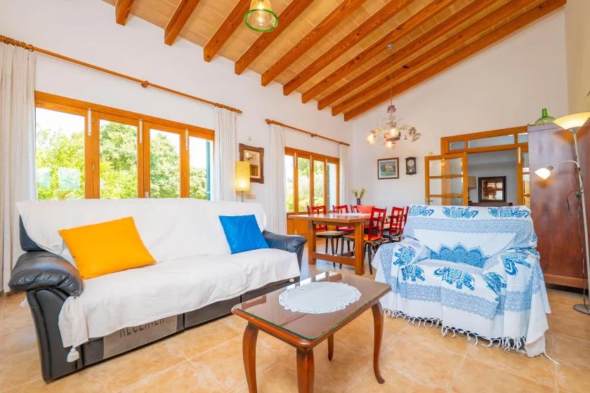 A bright living room has seating, a coffee table, and a dining area by the windows.