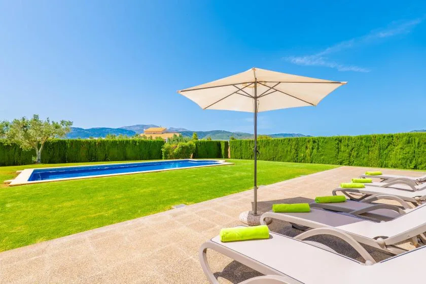 A sunny outdoor pool area with lounge seating beside the water.