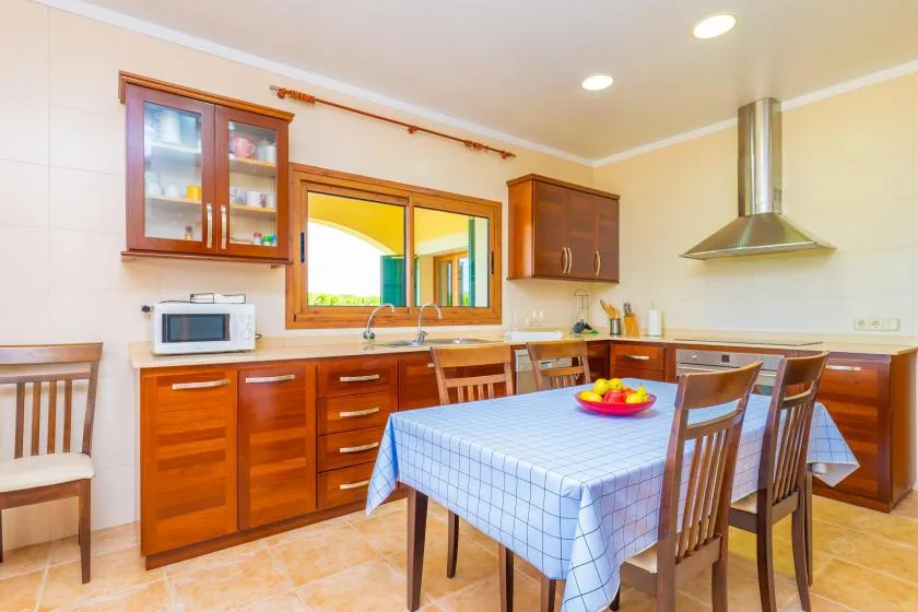 A kitchen and dining area with wooden cabinets and a table set with a blue cloth.