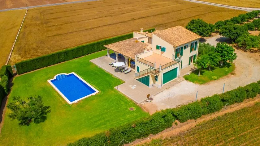 Aerial view of a house with a swimming pool and surrounding fields.