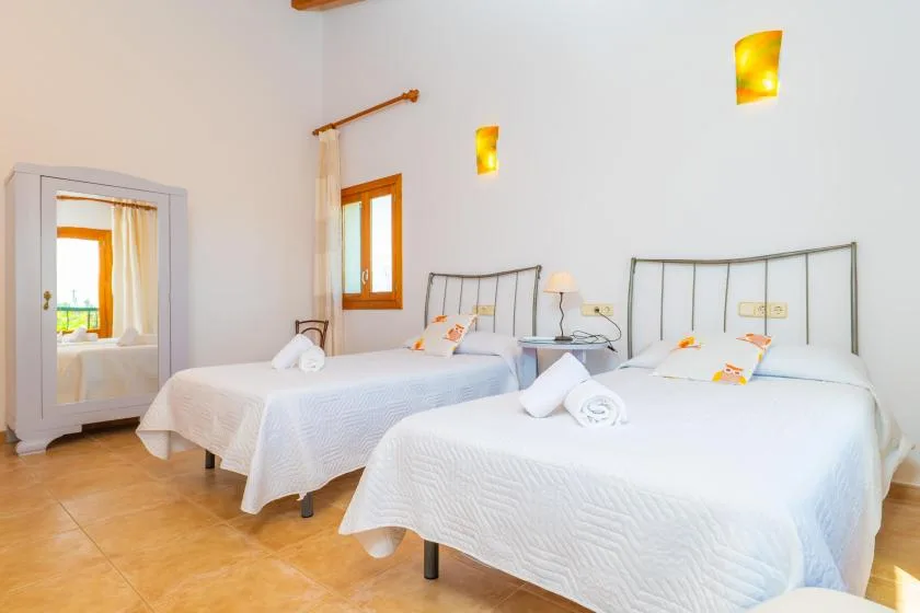 A bright bedroom with two beds dressed in white linens.