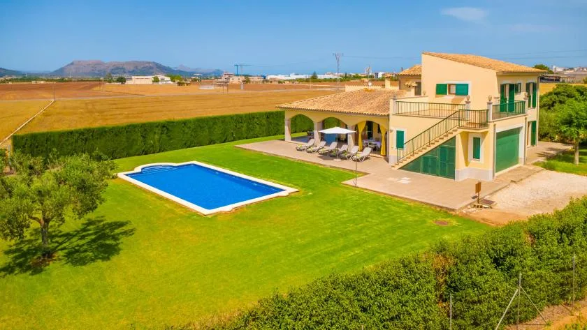 A landscaped property with a blue swimming pool beside a two-story building.