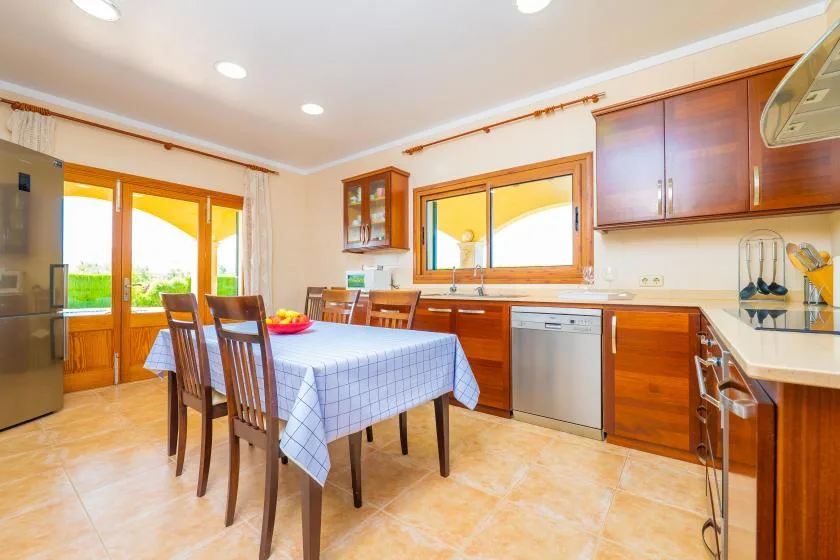 A bright kitchen with wooden cabinetry and a dining table set with a blue checkered cloth.