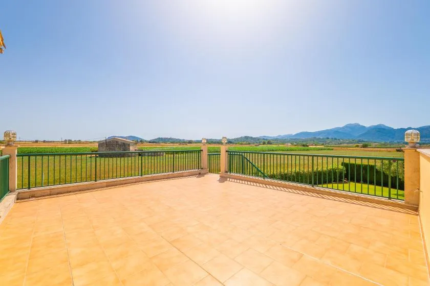 A spacious outdoor terrace overlooks green fields and distant mountains.