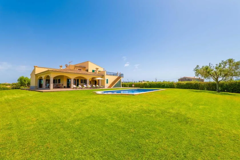 A house and swimming pool sit beside a broad green lawn.