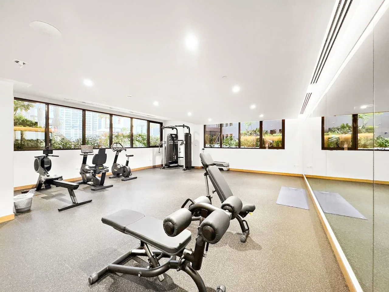 Un gimnasio interior luminoso con máquinas de ejercicio y una pared con espejo.