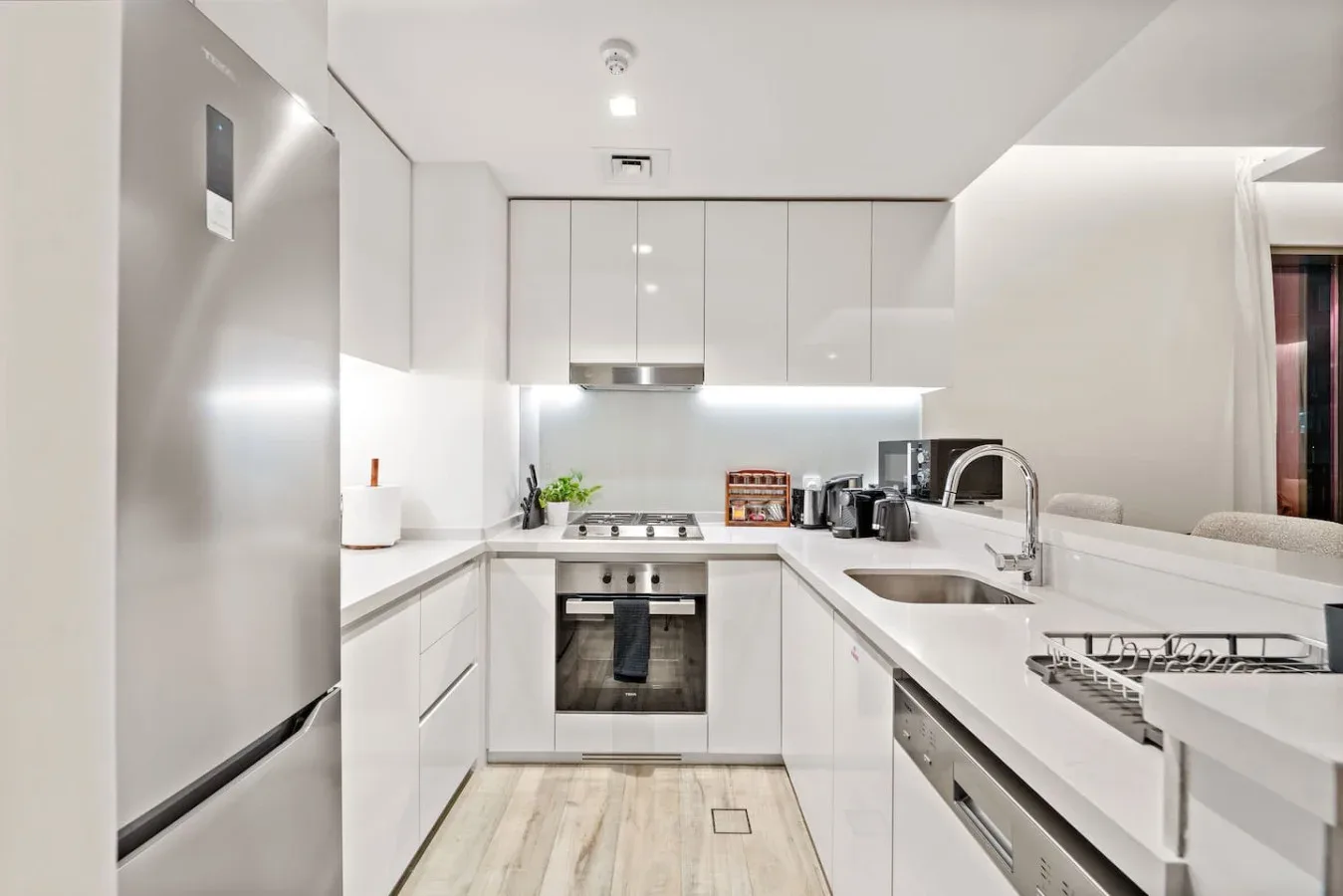 Una cocina moderna y luminosa con gabinetes blancos, encimera y fregadero.