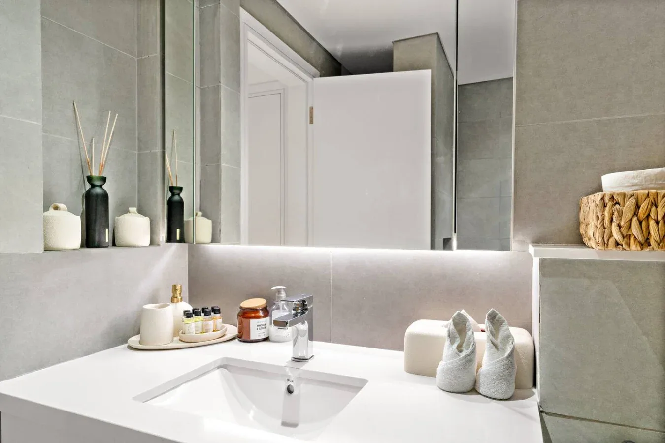 Un lavabo de baño con espejo y artículos de aseo sobre la encimera.