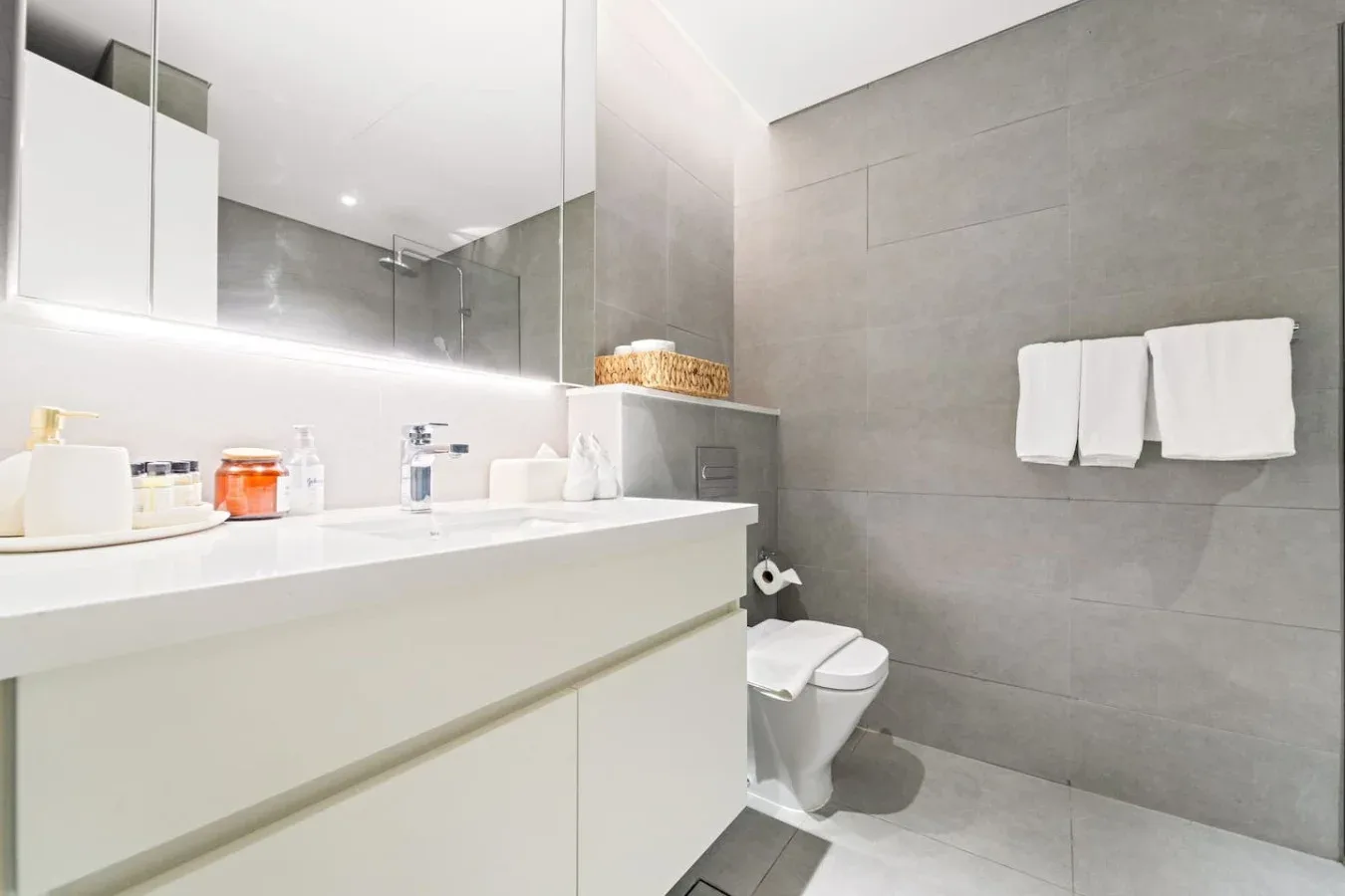 Un baño moderno con un lavabo blanco y paredes de azulejos grises.