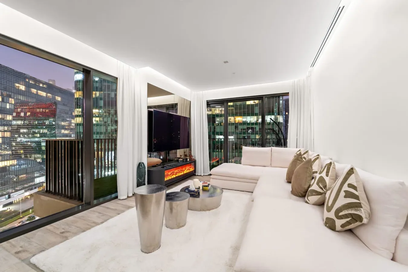 Una sala luminosa con asientos seccionales y grandes ventanales con vistas a edificios de la ciudad.