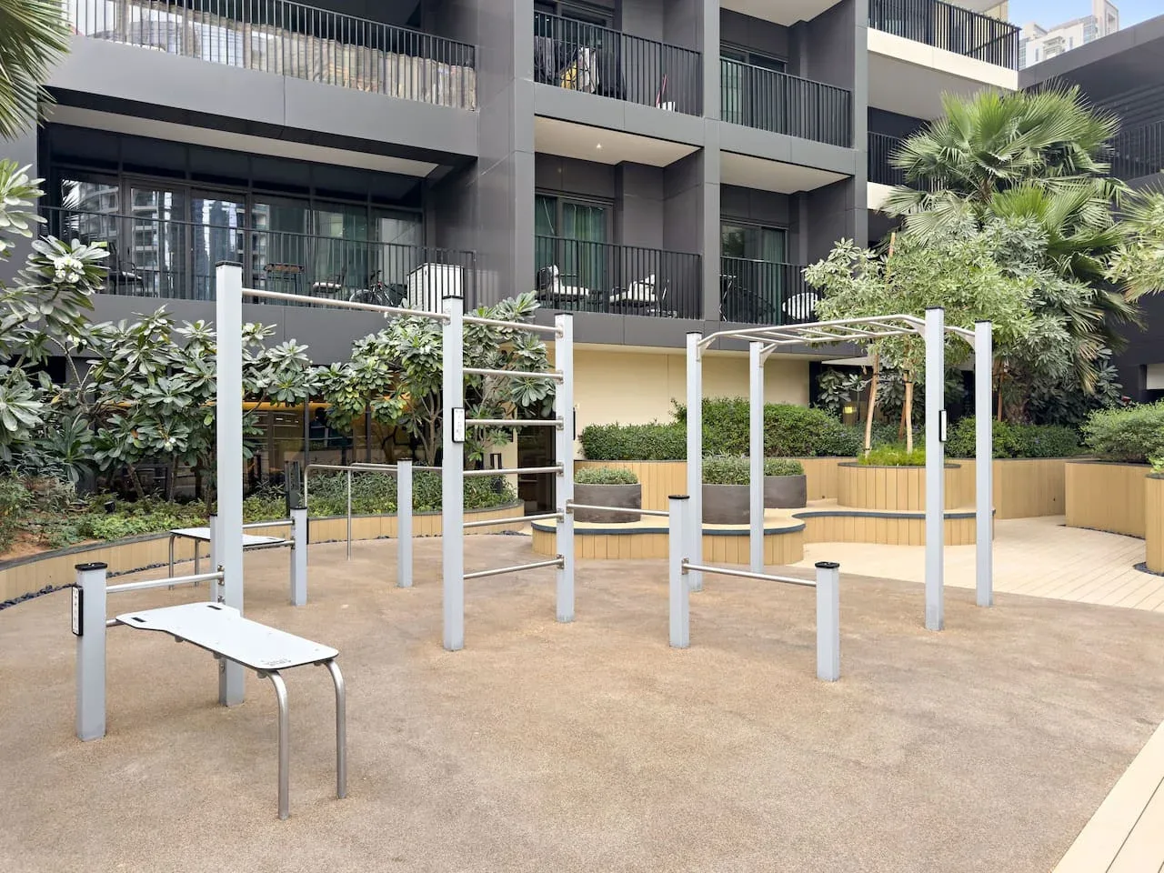Una zona de ejercicio al aire libre con barras metálicas y jardineras.