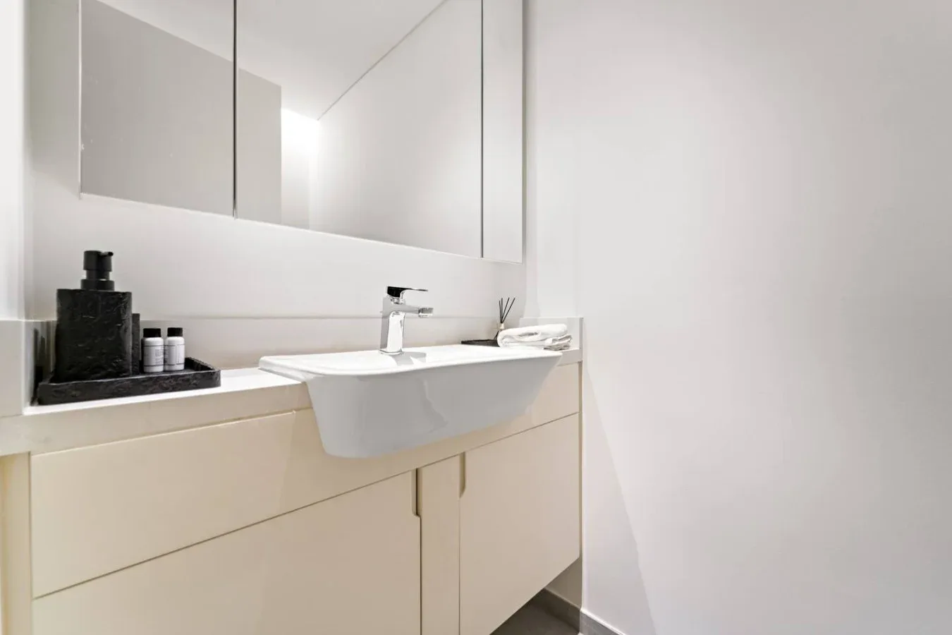 Un lavabo de baño luminoso con espejo y artículos de aseo sobre la encimera.