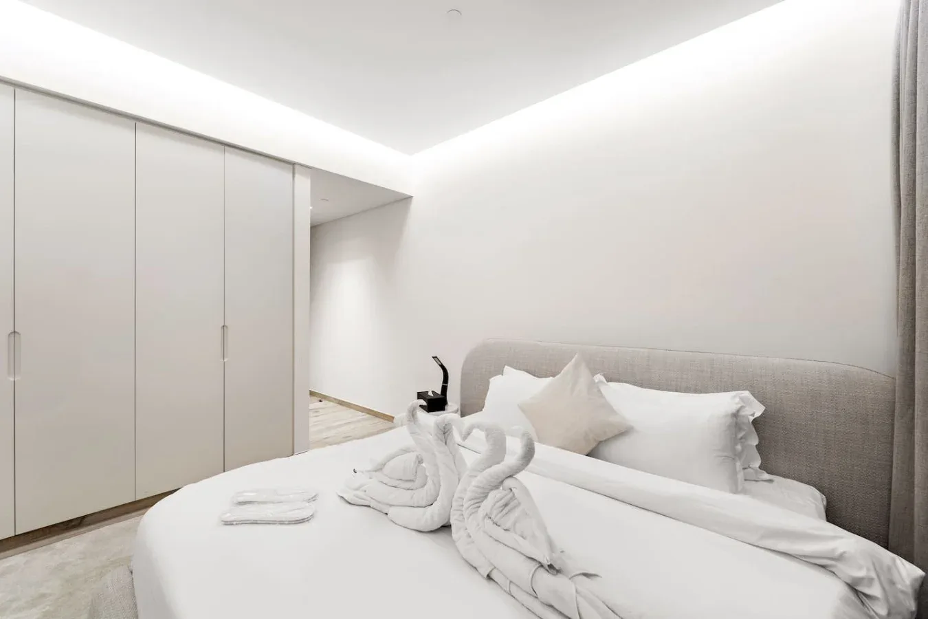Un dormitorio luminoso con una cama tendida y armarios empotrados.