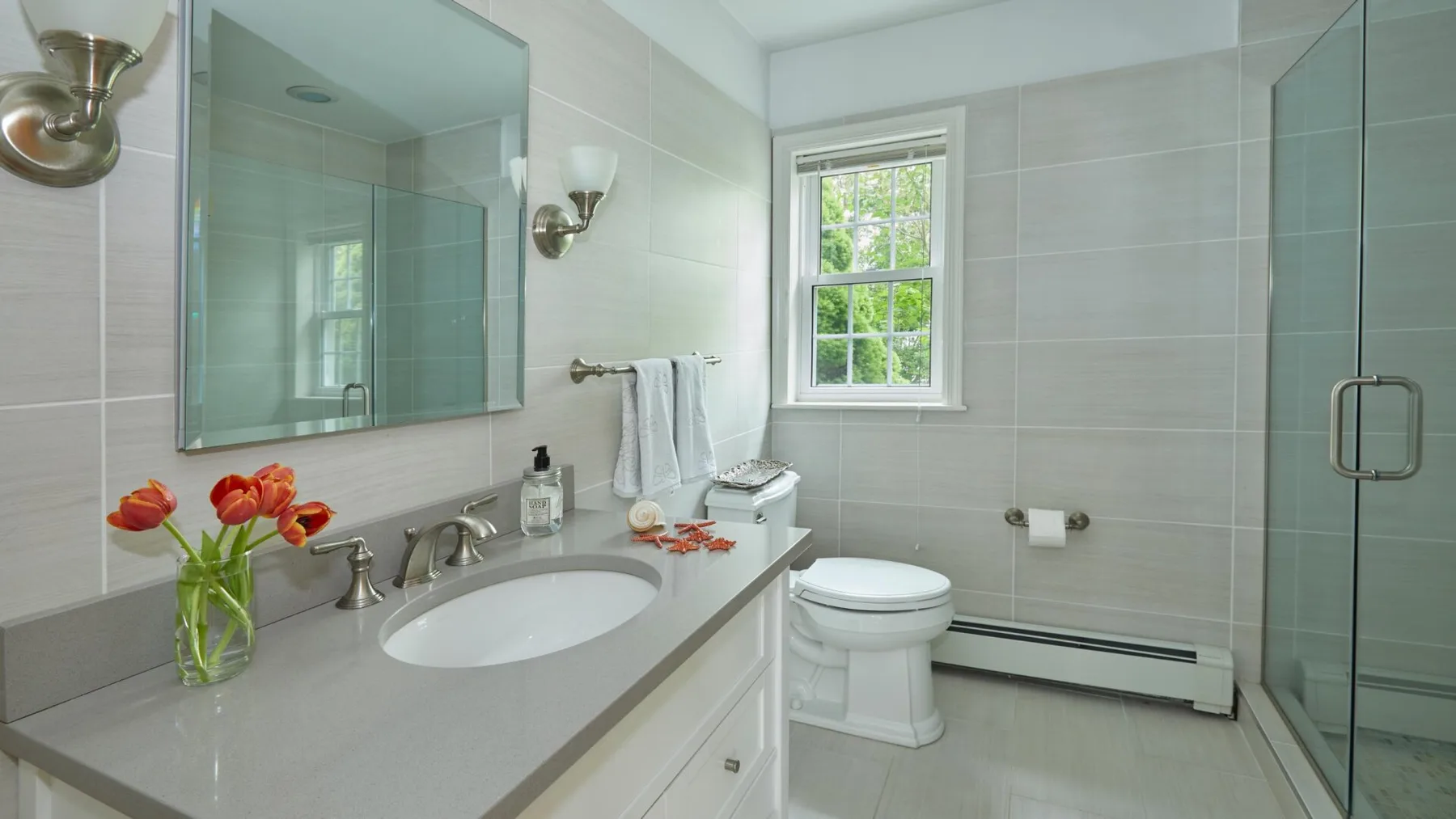 Un baño luminoso con lavabo, inodoro y ducha de vidrio.