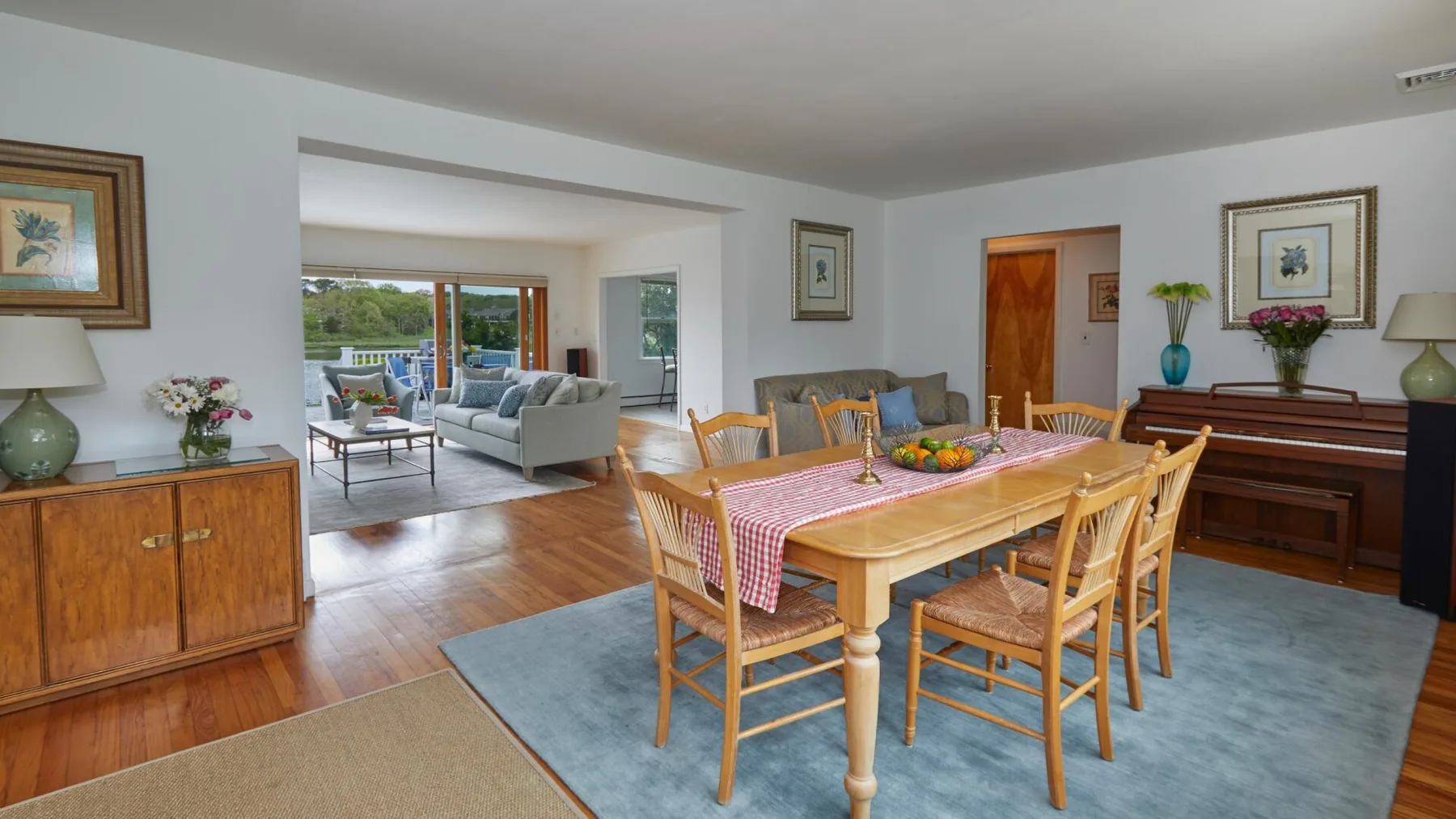 Comedor con una mesa de madera junto a una sala de estar abierta.