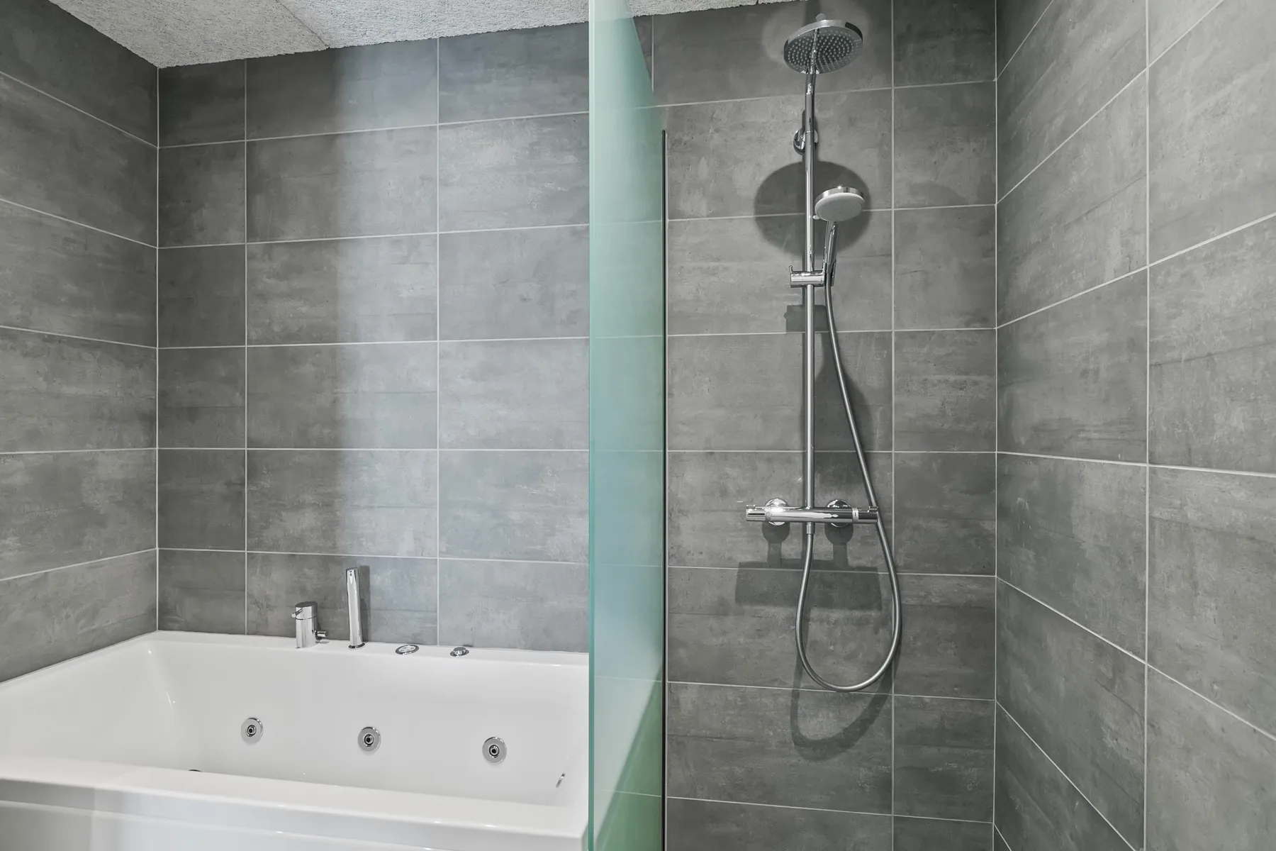 Un baño alicatado con bañera y ducha de pared.