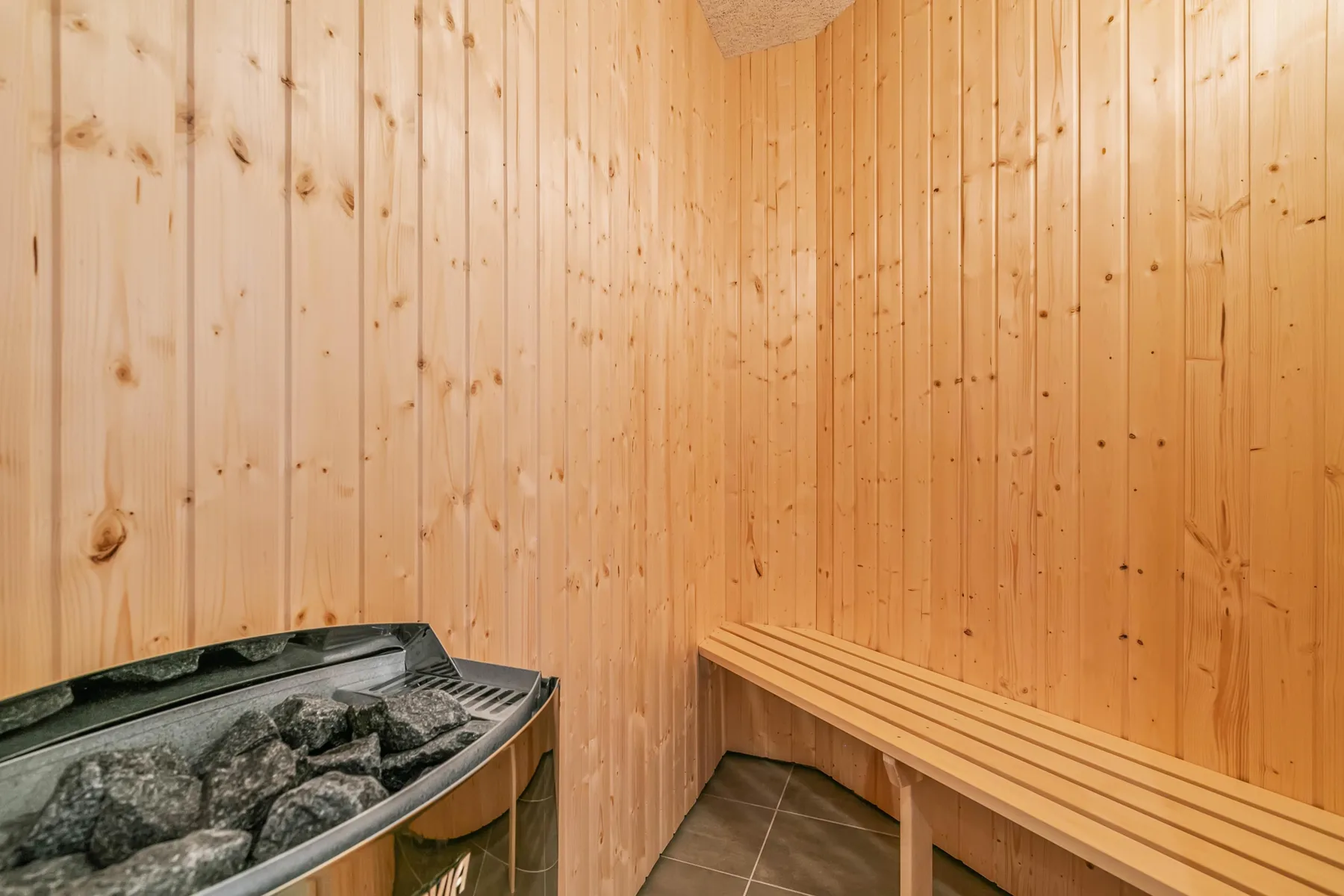 Una sauna revestida de madera con un banco y un calentador de piedras.
