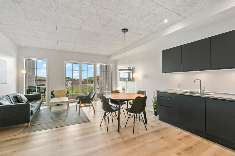 Una luminosa sala de estar y comedor abiertos, con cocina y grandes ventanales.