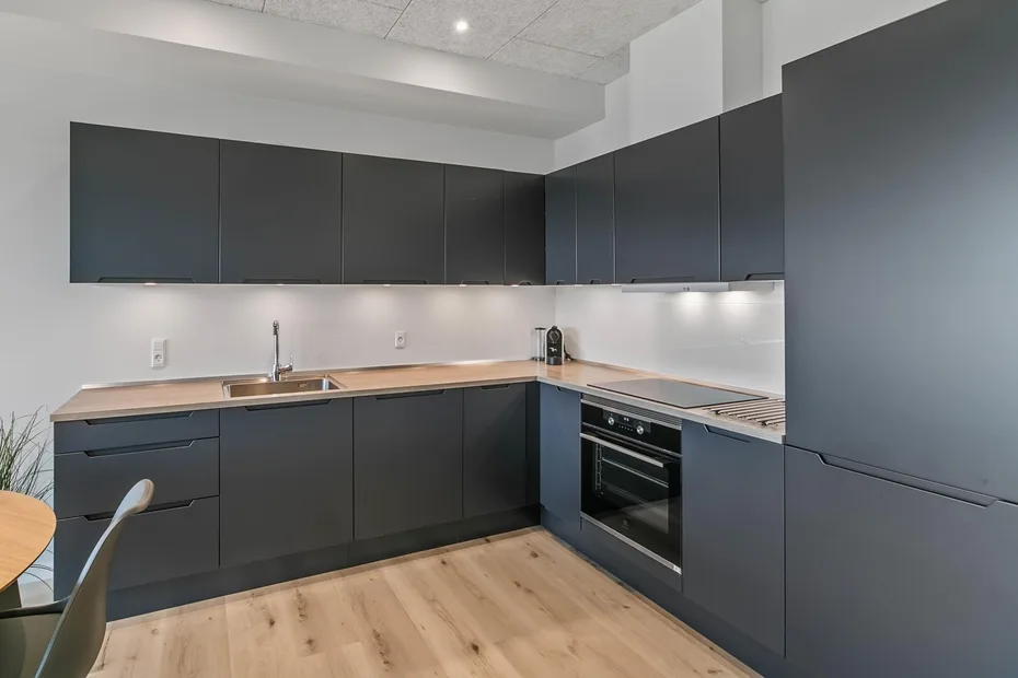 Una cocina moderna con gabinetes oscuros, una encimera y electrodomésticos de cocina integrados.
