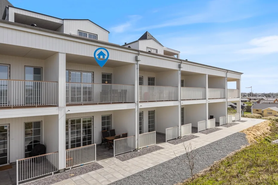 Un largo edificio residencial de dos pisos con balcones y un sendero pavimentado.