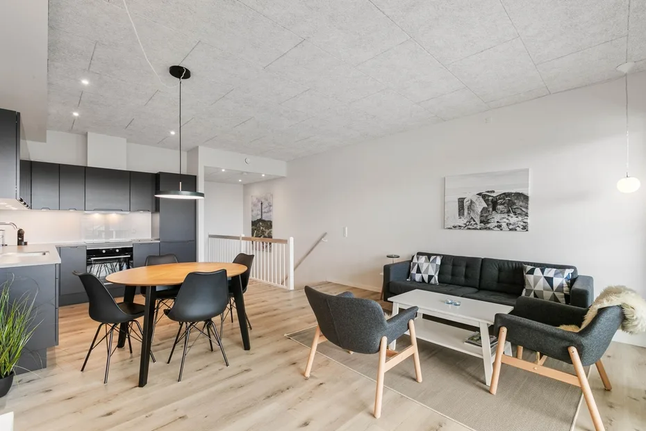 Una sala de estar y comedor diáfana con un sofá oscuro y una mesa de comedor.