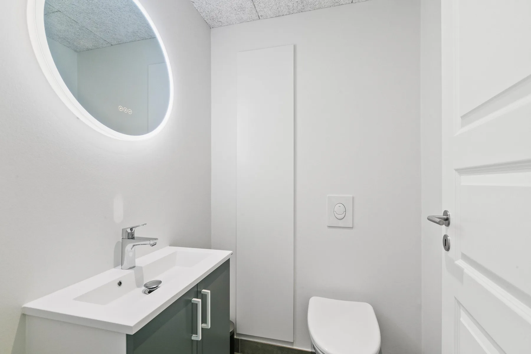 Un baño luminoso con lavabo, espejo ovalado e inodoro.