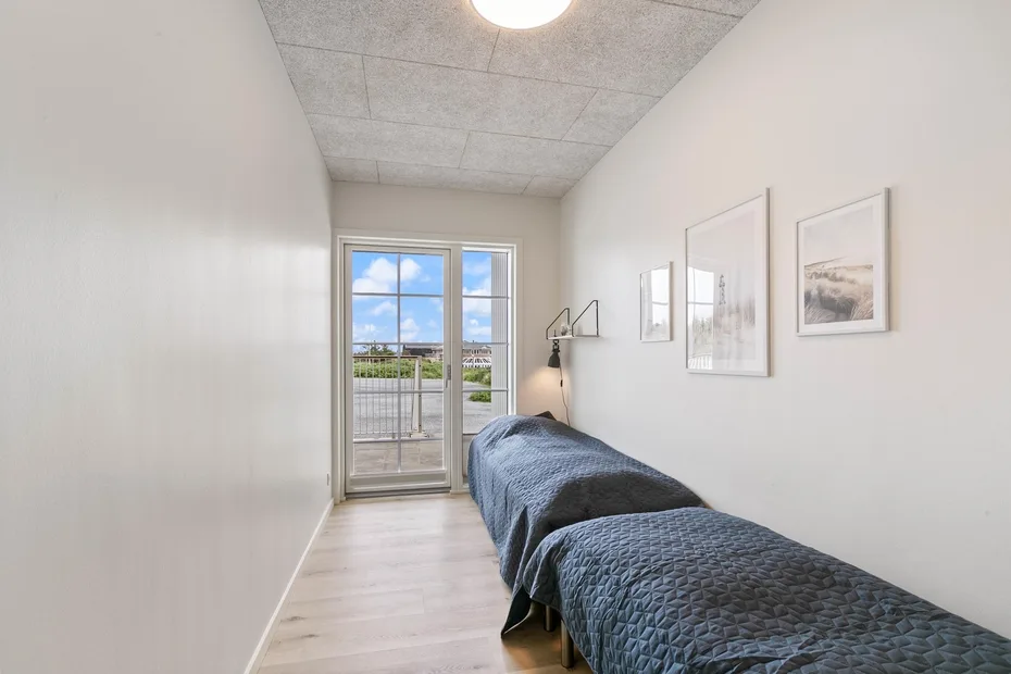 Un dormitorio estrecho con una cama junto a una ventana grande.