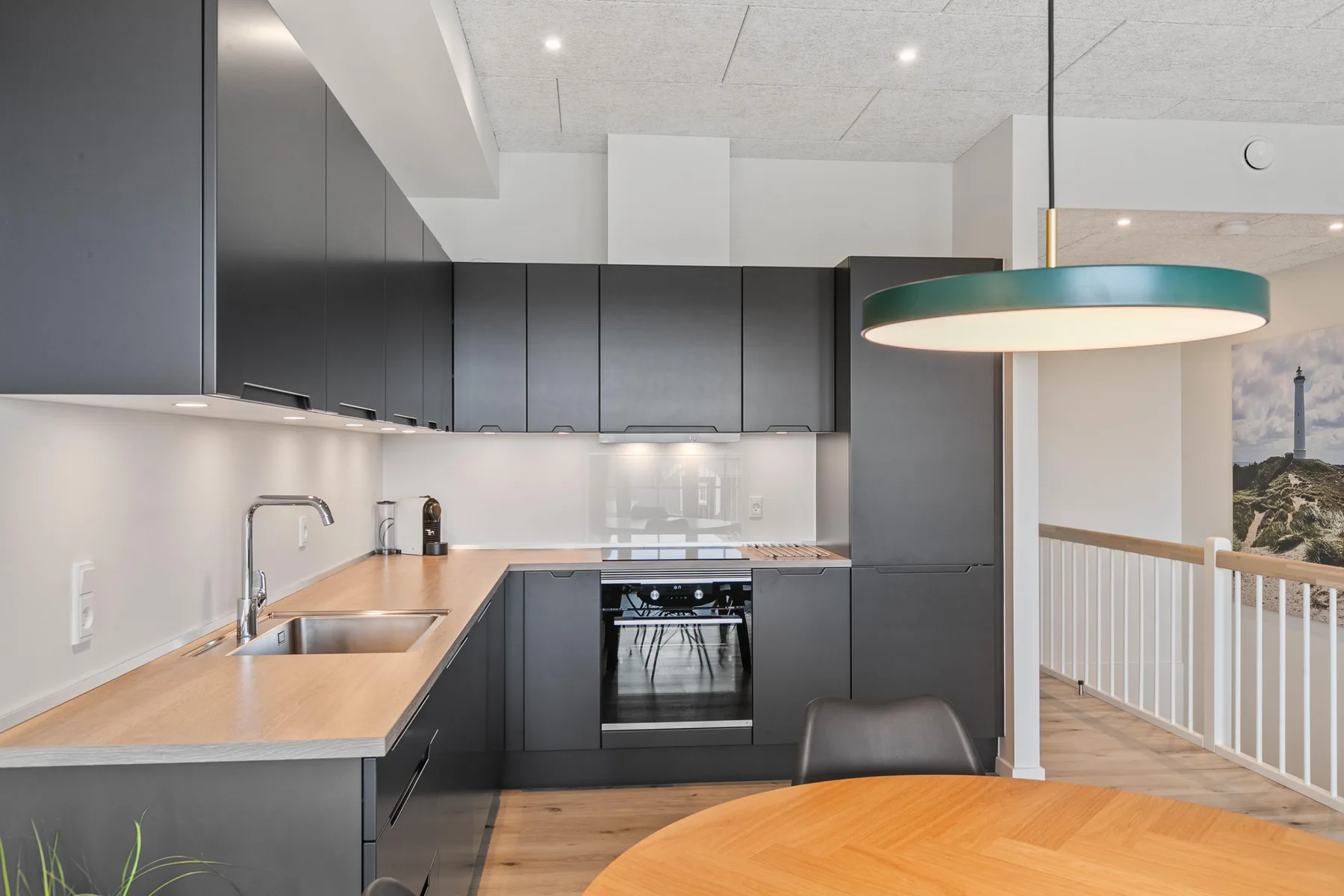 Una cocina moderna con gabinetes oscuros, una encimera de madera y una mesa de comedor.